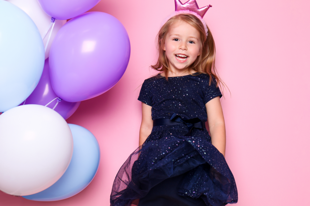 little girl pink background with balloons and pink crown